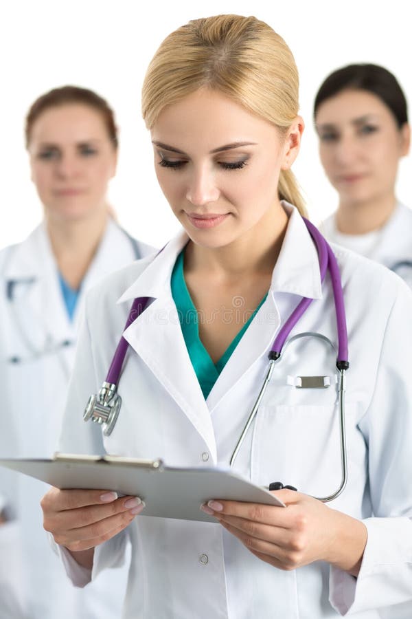 Portrait of young blonde female doctor surrounded by medical team, looking at file with documents. Healthcare and medicine concept.