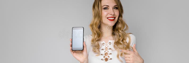 Portrait of a young blonde girl. Young girl holding a phone in her hand