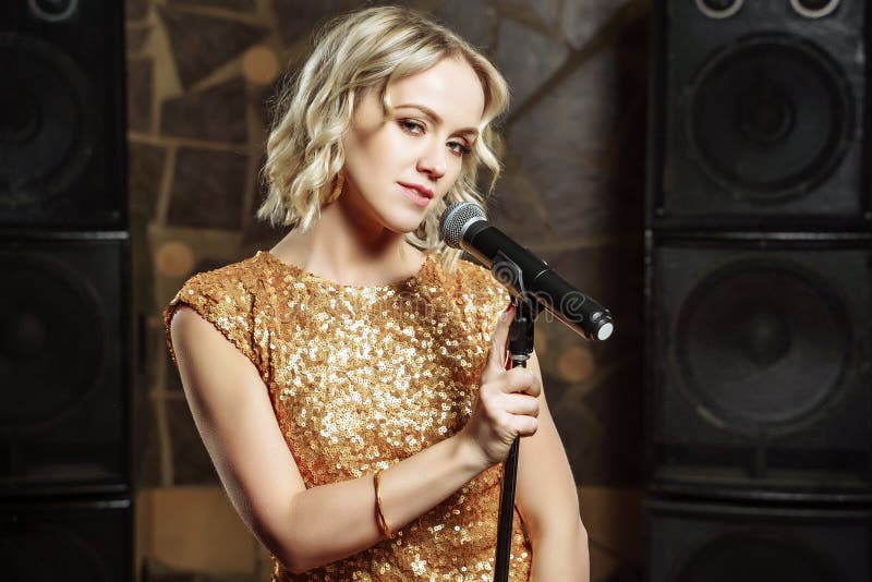Portrait of young blonde woman with microphone on dark background stock photography Portrait of young blonde woman with microphone on dark background stock photography