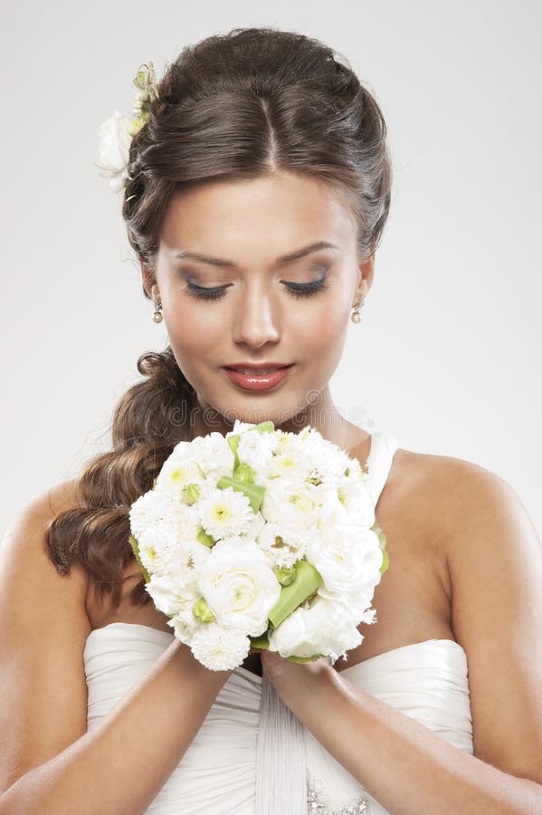 Portrait of a young brunette bride holding flowers