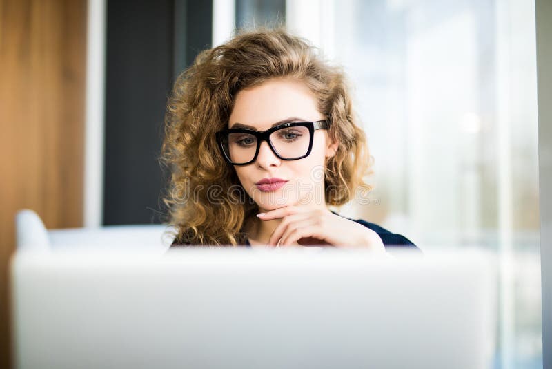 Portrait of a young business woman in glasses using laptop at office stock images Portrait of a young business woman in glasses using laptop at office stock images