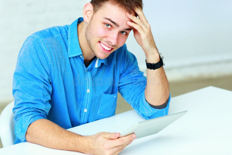 Portrait of a young businessman holding tablet computer and looking at the camera