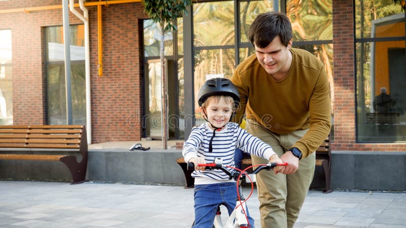 Portrait of young caring father teaching his little son riding a bicycle stock photo Portrait of young caring father teaching his little son riding a bicycle stock photo