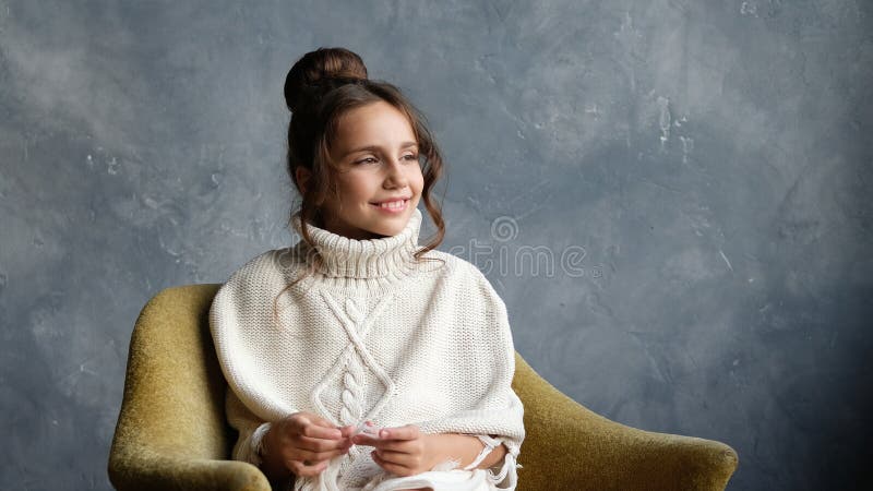 Teen age girl sitting on the old-fashioned yellow chair, smiling, looking at the right side.