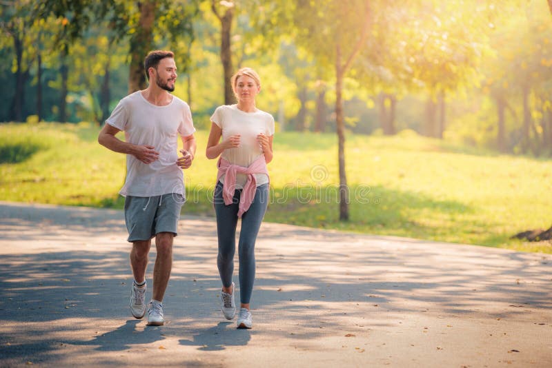 Portrait of Young couple running in the park at sunset. Concept sport and love. Warm tone.