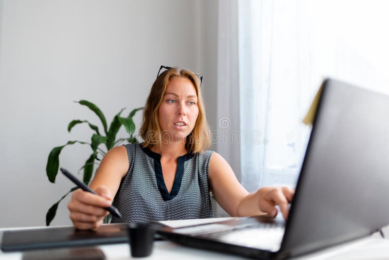 Portrait of a young female worker drawing on a tablet and working on a laptop. Freelance and creative work