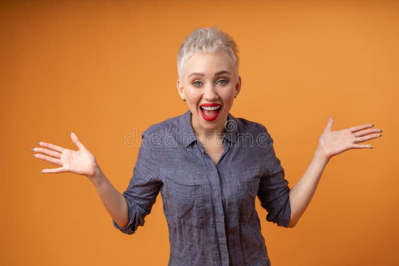 Portrait of young girl with blond short hairstyle looking at camera and laugh isolated on orange background with copy space royalty free stock images Portrait of young girl with blond short hairstyle looking at camera and laugh isolated on orange background with copy space royalty free stock images