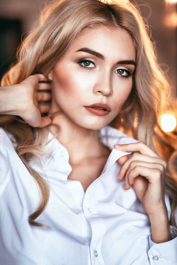 Portrait of a young girl looking into the camera. Model posing in a white shirt stock photo Portrait of a young girl looking into the camera. Model posing in a white shirt stock photo