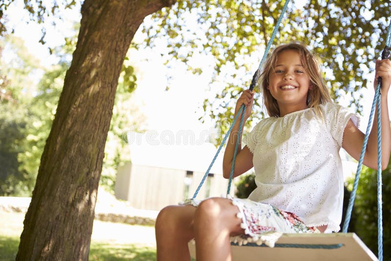 Portrait Of Young Girl Playing On Tree Swing