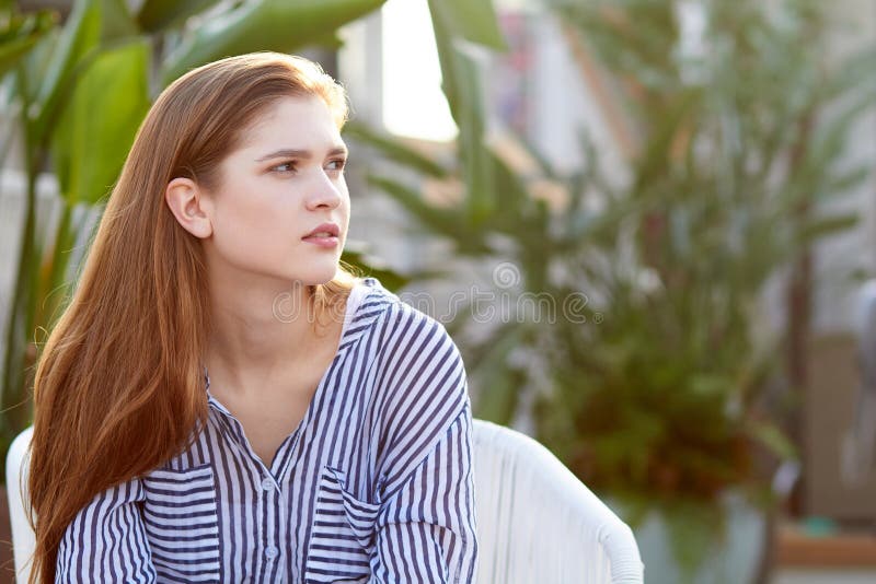 Portrait of young girl sits in the white armchair against blurred balckground stock image Portrait of young girl sits in the white armchair against blurred balckground stock image
