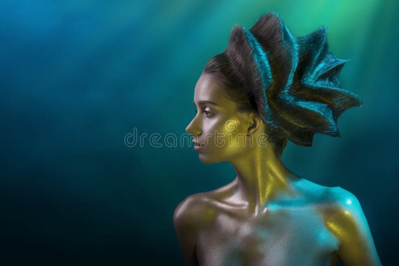 Portrait of the young girl with a vanguard hairstyle and the shine make-up in yellow-blue tones on a blue background royalty free stock photo Portrait of the young girl with a vanguard hairstyle and the shine make-up in yellow-blue tones on a blue background royalty free stock photo