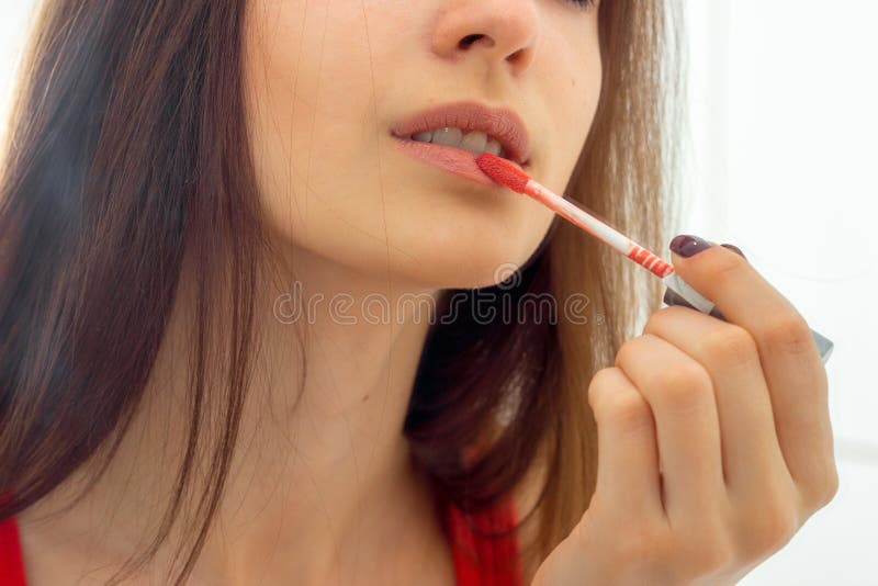 Portrait of a young girl who paints her lips red glitter close-up