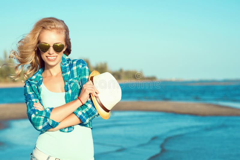 Portrait of young gorgeous suntanned blond wearing mirrored heart shaped sunglasses and checked blue shirt at the seaside stock image Portrait of young gorgeous suntanned blond wearing mirrored heart shaped sunglasses and checked blue shirt at the seaside stock image