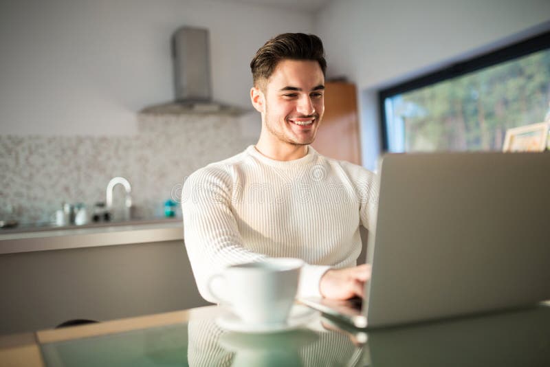 Young happy man working at home on laptop stock photography