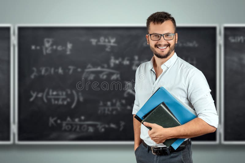 Portrait of a young male teacher on the background of the school blackboard. Teacher`s Day Knowledge Day back to school study. Beautiful, board.