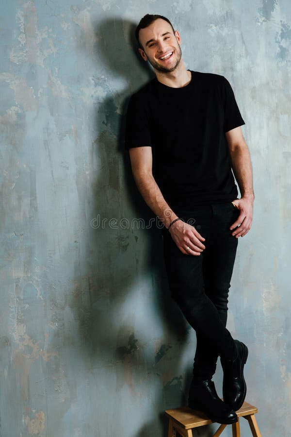 Portrait of a young man in a black T-shirt leaned against a vintage gray wall. Copy space. royalty free stock photo Portrait of a young man in a black T-shirt leaned against a vintage gray wall. Copy space. royalty free stock photo