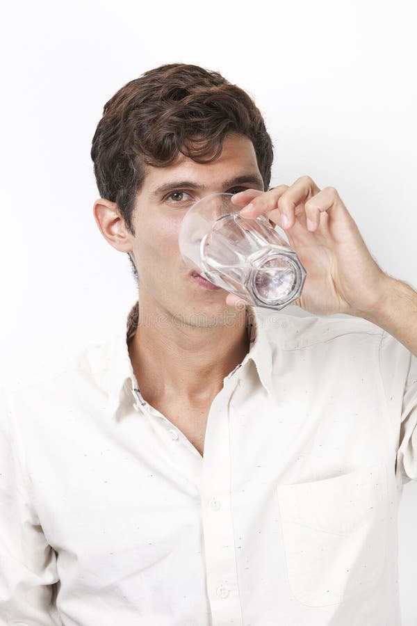 Portrait of young man drinking water against white background
