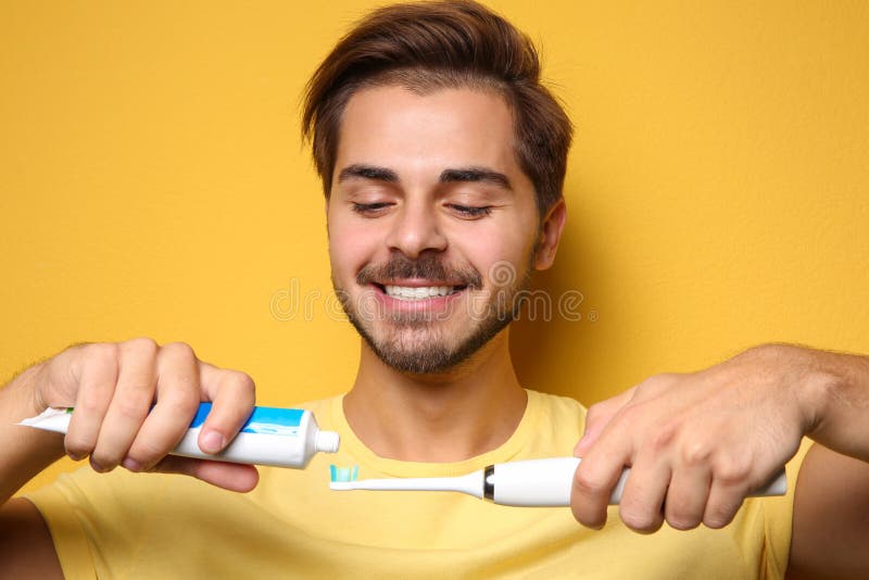 Portrait of young man with electric toothbrush and paste