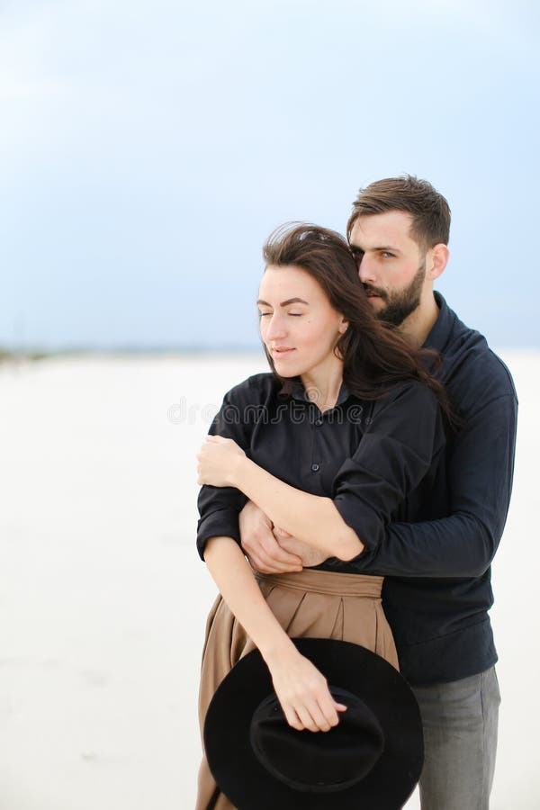 Portrait of young man hugging woman in monophonic background.