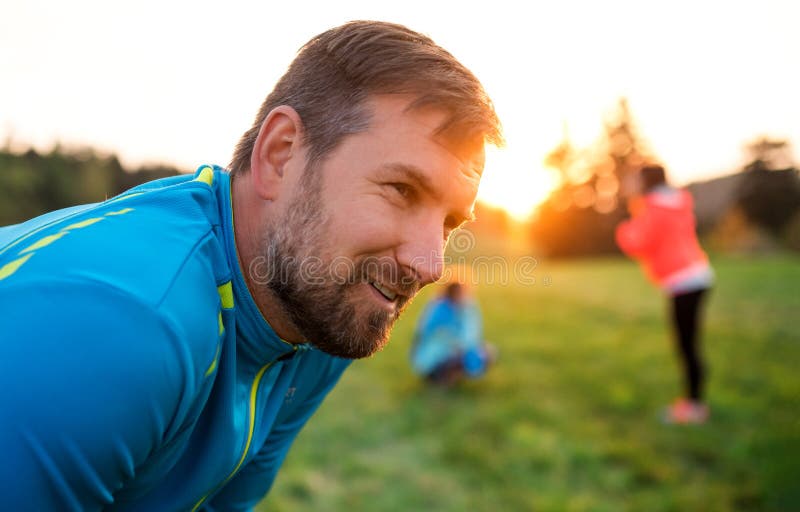 A portrait of young man with large group of people doing exercise in nature. stock image