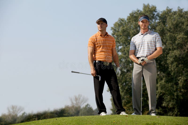 Portrait of Young Men Standing with Golf Sticks on Golf Course Stock