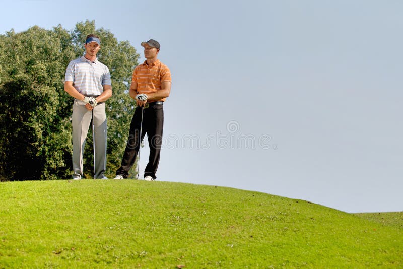Portrait of Young Men Standing with Golf Sticks on Golf Course Stock