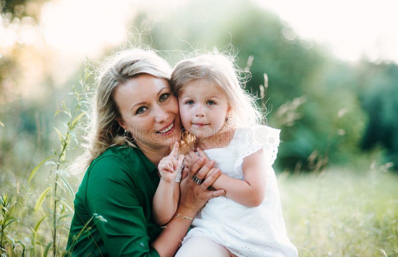 A portrait of young mother in nature with small daughter in summer. stock photos A portrait of young mother in nature with small daughter in summer. stock photos