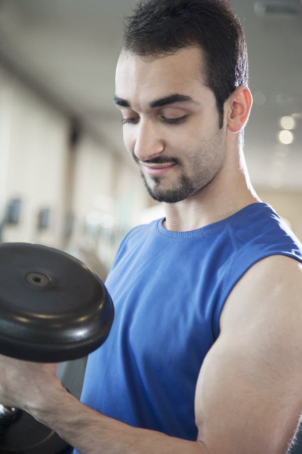 Portrait of young muscular man lifting weights in the gym stock images Portrait of young muscular man lifting weights in the gym stock images