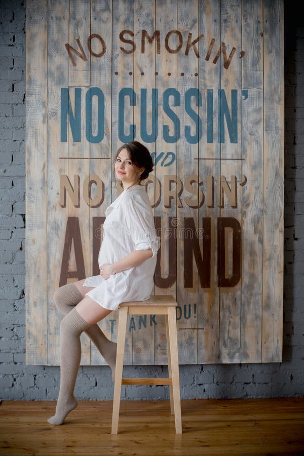 Portrait of a young pregnant woman in white shirt in photo Studio