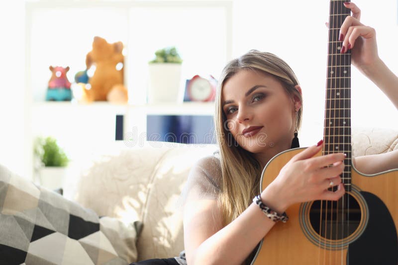 Young pretty woman playing on guitar, talented artist spend free time learning new song on musical instrument royalty free stock images