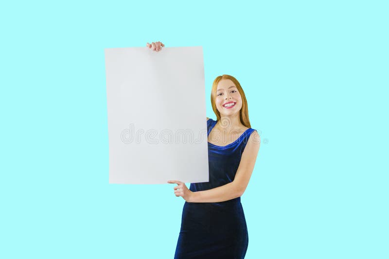 Portrait of a young red-haired girl who holds both hands along the length of the poster looking at the camera and stock photo Portrait of a young red-haired girl who holds both hands along the length of the poster looking at the camera and stock photo
