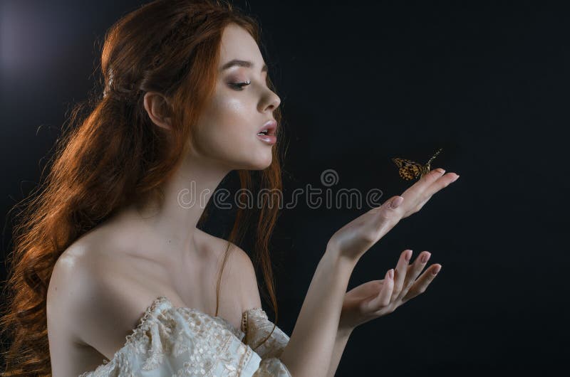 Portrait of a young red-haired woman in a vintage ash dress with open back and shoulders in the moonlight on a black background. S