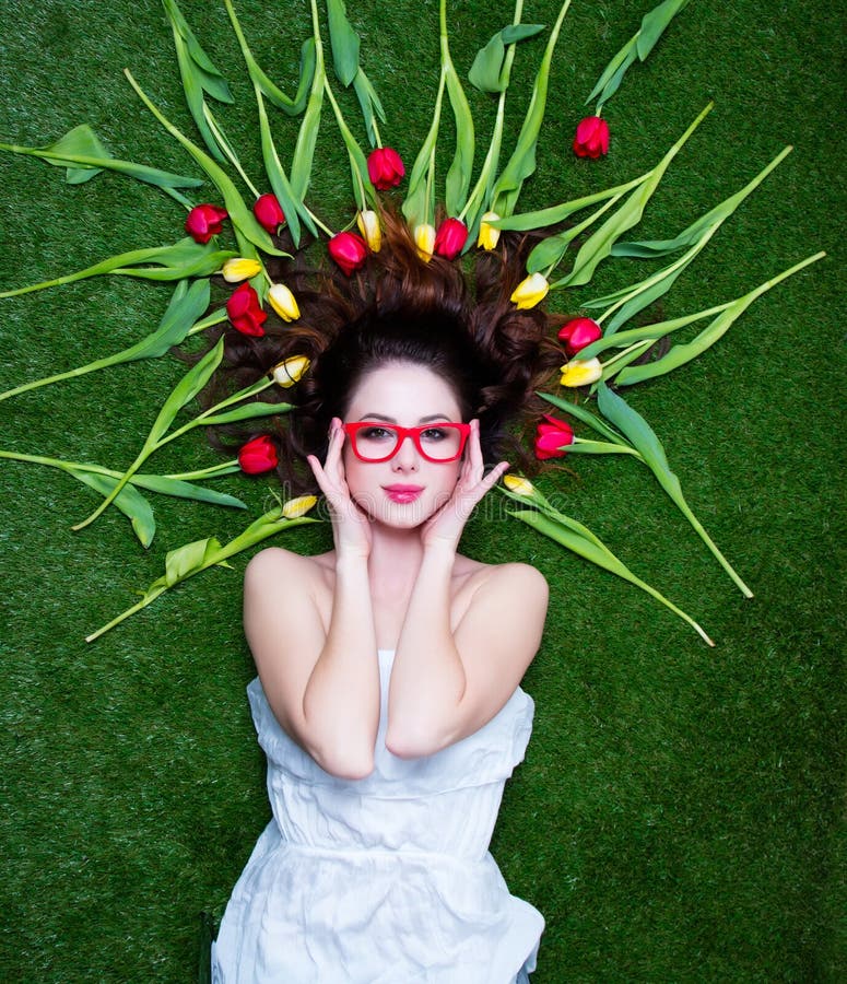 Portrait of a young redhead woman with tulips and glasses