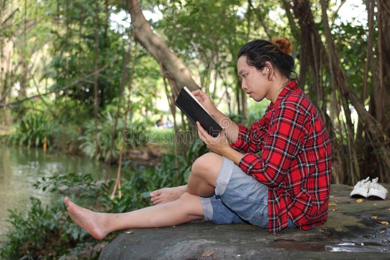 Portrait of young relaxed man in red shirt reading a book in beautiful nature background. royalty free stock photo Portrait of young relaxed man in red shirt reading a book in beautiful nature background. royalty free stock photo