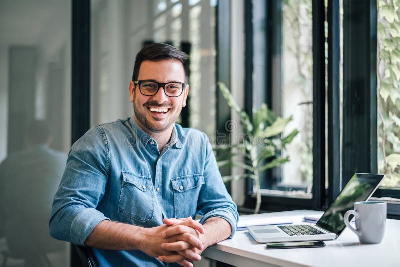 Portrait of young smiling happy handsome successful businessman entrepreneur freelancer working from home office on laptop royalty free stock images