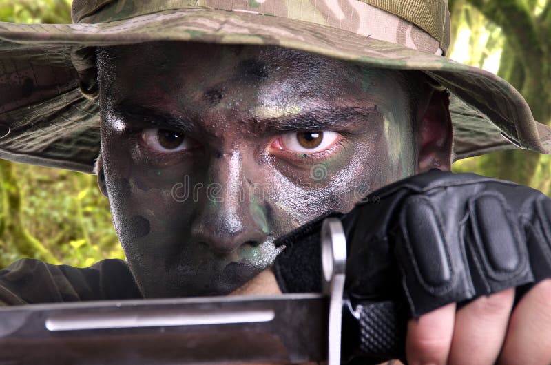 Portrait of a young soldier painted with jungle camouflage royalty free stock photo Portrait of a young soldier painted with jungle camouflage royalty free stock photo