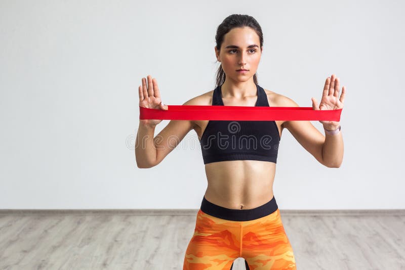 Portrait of young sporty woman wearing black top and orange leggings performs exercises for the muscles of the hands, workout with royalty free stock photos Portrait of young sporty woman wearing black top and orange leggings performs exercises for the muscles of the hands, workout with royalty free stock photos