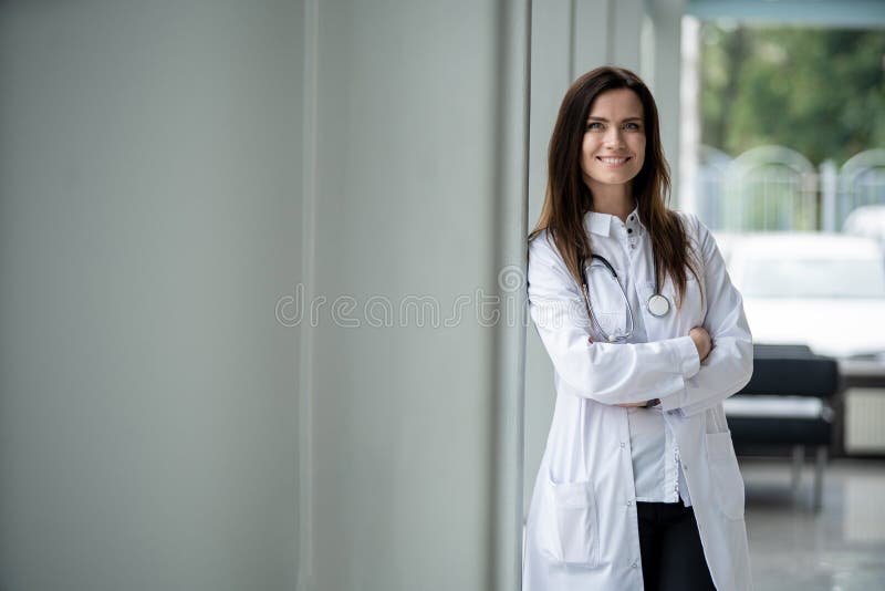 Portrait of young woman doctor with white coat standing in hospital.