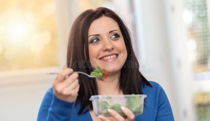 Portrait of young woman eating salad, light effect