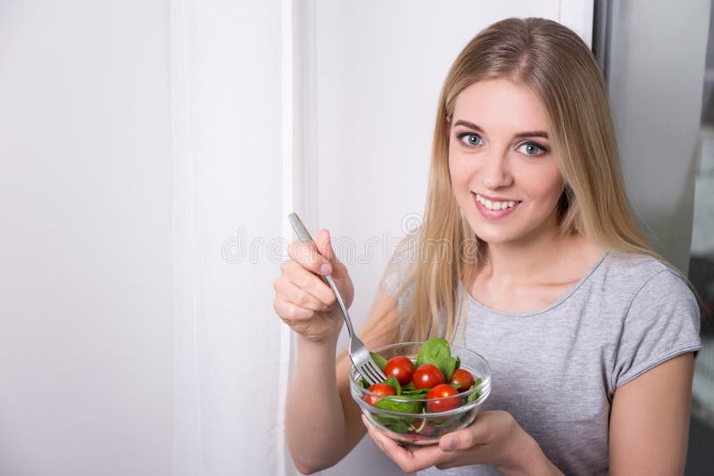 Portrait of young woman eating salad with tomatoes and spinach