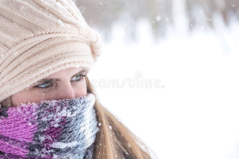 Winter portrait of beautiful blond woman with scarf over nose and mouth to protect from the frost.