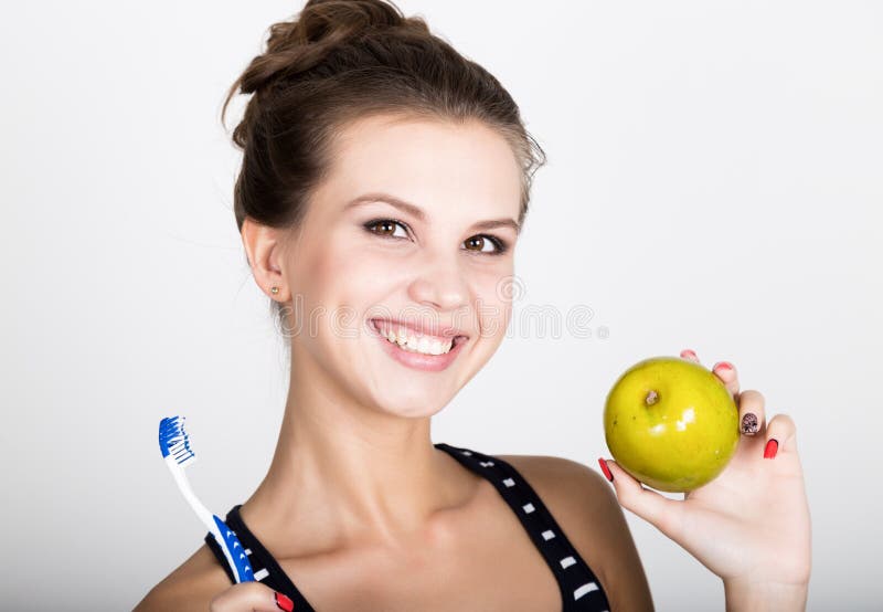 Portrait of young woman holding an apple and toothbrush, dental health concept stock image Portrait of young woman holding an apple and toothbrush, dental health concept stock image