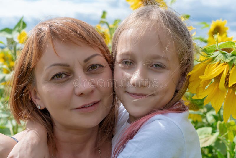 Portrait of a young woman and little girl outdoors.Sweet little girl is hugging her beautiful young mom standing in a large field stock photography Portrait of a young woman and little girl outdoors.Sweet little girl is hugging her beautiful young mom standing in a large field stock photography