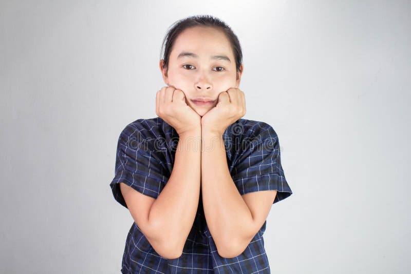 Portrait Of Young Woman Looking Bored And Put Hands On Chin Isolated On A Grey Background Stock