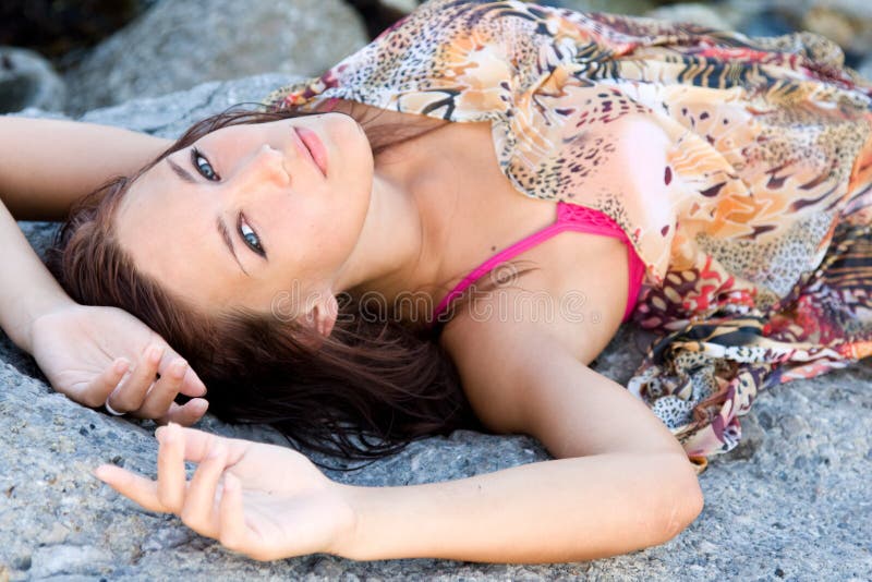 Portrait of a young woman lying on a rock