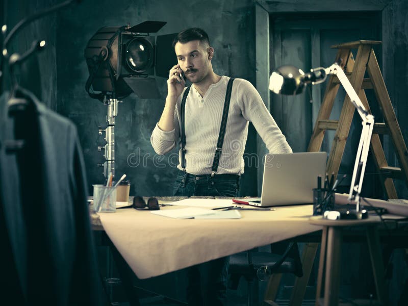 Portrait of a bearded businessman who is working with his notebook and mobile phone at loft studio or home. Portrait of a bearded businessman who is working with his notebook and mobile phone at loft studio or home.