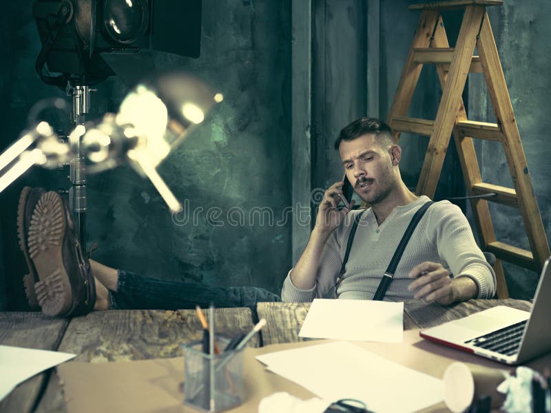 Portrait of a bearded businessman who is working with his notebook and mobile phone at loft studio or home. Portrait of a bearded businessman who is working with his notebook and mobile phone at loft studio or home.