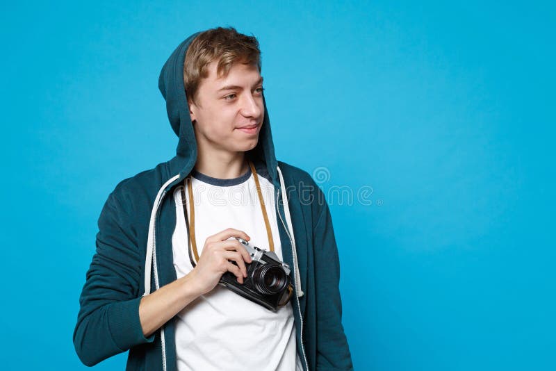 Portret die van de vrij jonge mens die in vrijetijdskleding, retro uitstekende die fotocamera opzij kijken houden op blauw wordt royalty-vrije stock fotografie Portret die van de vrij jonge mens die in vrijetijdskleding, retro uitstekende die fotocamera opzij kijken houden op blauw wordt royalty-vrije stock fotografie