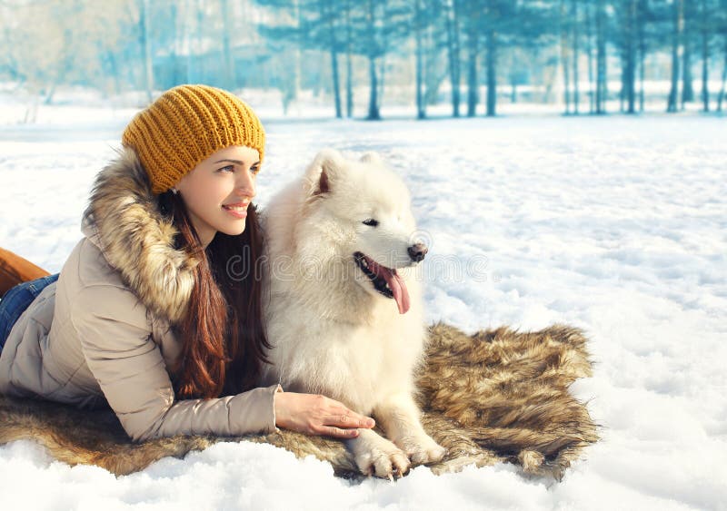 Portrait of woman and white Samoyed dog lying on the snow in winter day. Portrait of woman and white Samoyed dog lying on the snow in winter day