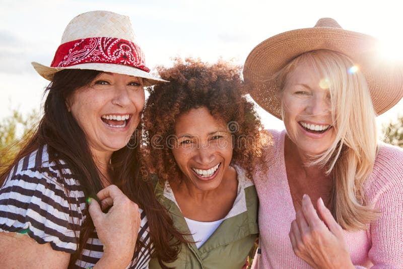 Portrait Of Mature Female Friends Walking Through Field On Camping Vacation. Portrait Of Mature Female Friends Walking Through Field On Camping Vacation